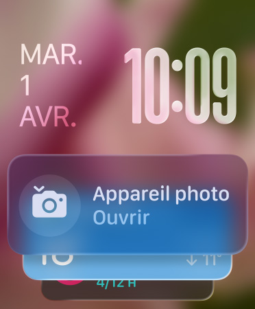 Le widget Appareil photo apparaît au bas de l’écran, l’heure en chiffres translucides en haut à droite, et la date en haut à gauche