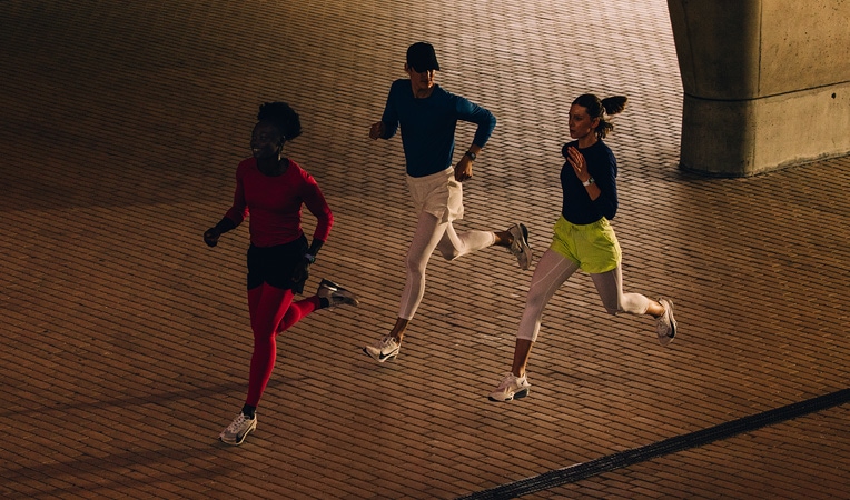 Földön ülő nő, ahogyan a karját a lábához nyújtja, miközben Apple Watch Series 10-et visel, amelynek kijelzőjén az Edzés, a Levezetés, a Tevékenység és a Tevékenységgyűrűk jelennek meg