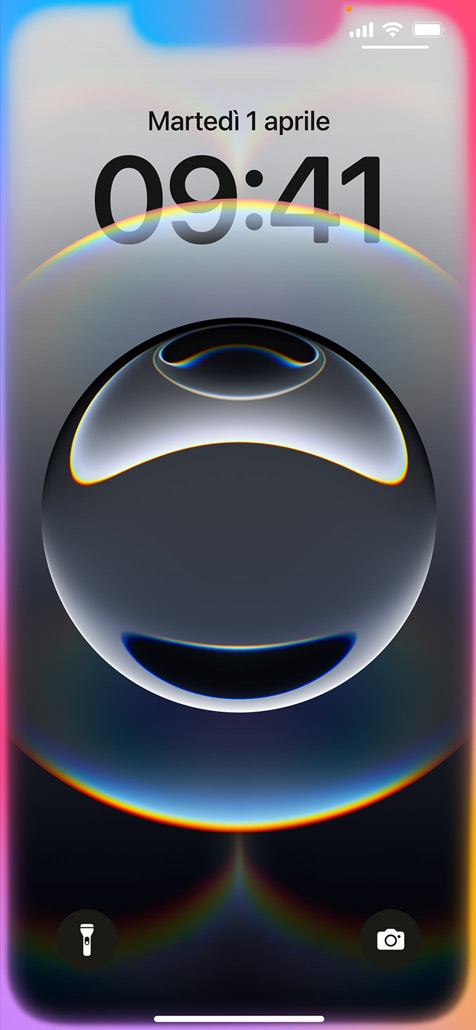 Una mano che tiene un iPhone 16e con la schermata di blocco circondata da una luce colorata soffusa.