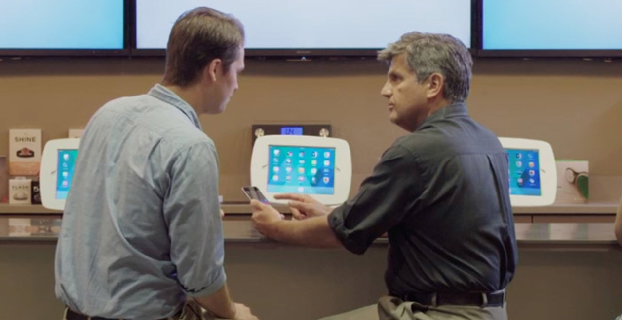 رجلان يجلسان أمام O Bar وينظران إلى شاشة iPhone.‏