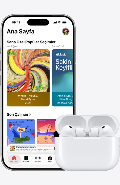 iPhone 17 Pro, önden dış görünüm, Ana Ekran’ın açık olduğu Apple Music uygulaması, açık MagSafe Şarj Kutusu’ndaki AirPods Pro 3’ün yanında duruyor