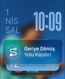 Birbirinden yavaşça uzaklaşan üç Apple Watch modeli; ortadaki Siyah Trail Loop kordona sahip Natürel Titanyum Apple Watch Ultra 2'nin kadranında fotoğraf görünüyor, sonra ekranda Akıllı Gruplama ipucu olarak küçük bir Geriye Dönüş simgesi beliriyor, Geriye Dönüş ekranı açılıyor, yukarıda Liquid Glass saat rakamları görünüyor; sağdaki Deniz Yeşili Örgü Solo Loop kordona sahip Simsiyah Apple Watch'un kadranında Büyükanne adlı kişiyle Canlı Çeviri özelliği kullanılarak yapılan bir konuşma görünüyor; soldaki Koyu Turuncu Spor kordona sahip Gümüş rengi Apple Watch'un kadranında Antrenman uygulamasında Koşu (Dış) yazısı ve oynat düğmesi görünüyor