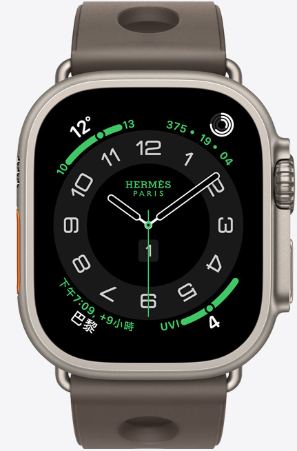 Apple Watch Hermès Ultra 3，展示原色鈦金屬錶殼、Hermès Circulaire 錶面與多項複雜功能，包括天氣、活動記錄圓圈、巴黎時間與紫外線指數，機身右側有數位錶冠、麥克風，以及凸起的側邊按鈕，搭配 Gris Titane 鈦灰色 Scub'H Diving 錶帶