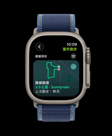 原色鈦金屬錶殼搭配藍色配亮藍色越野錶環的 Apple Watch Ultra 3，展示室外跑步體能訓練的路線競速功能