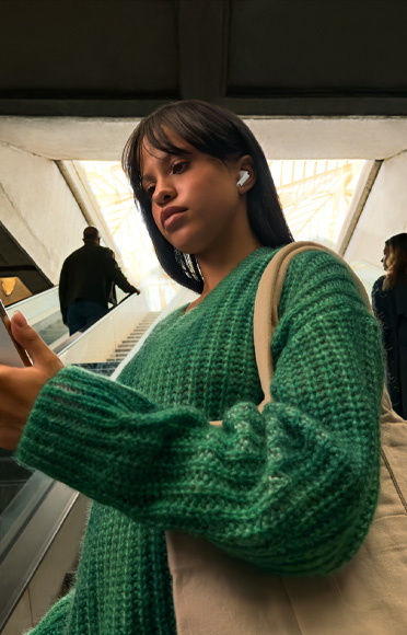 Inimene, kes kannab AirPods Pro 3 klappe vaatamas oma iPhone'i