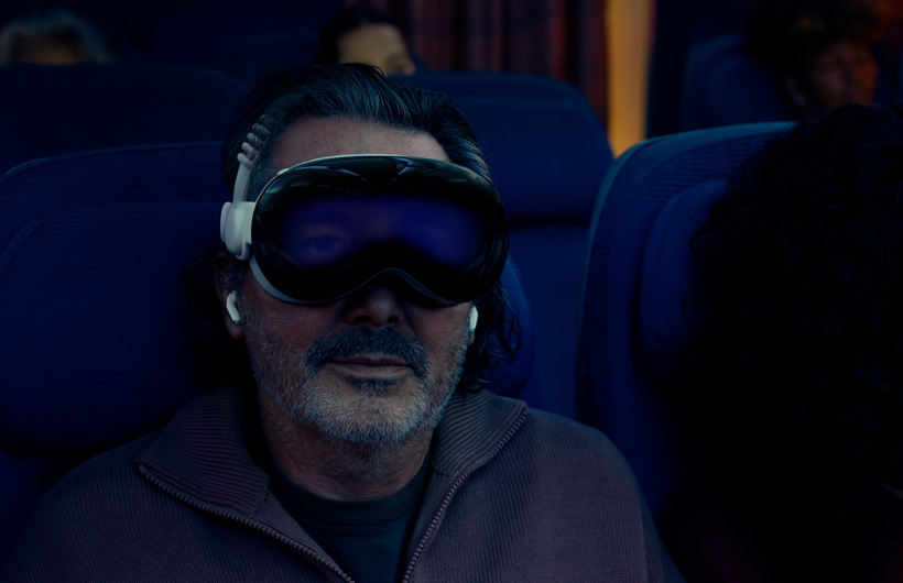 شخص يجلس في طائرة ويضع على وجهه Apple Vision Pro تم تجميعه مع الحزام الثنائي المغزول