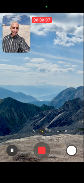 O persoană demonstrează funcția de înregistrare video duală filmându-se pe sine cu camera frontală și în același timp filmând munții cu camera spate