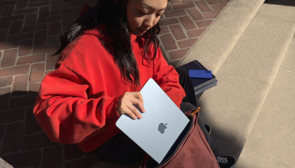 A student placing MacBook Air into their backpack